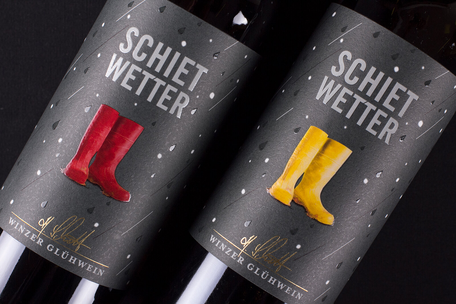 Schrägestellte Weinflaschen vom Schietwetter-Glüchwein mit Druckveredelungen versehen auf grauen Hintergrund mit Gummistiefel als Key Visual.